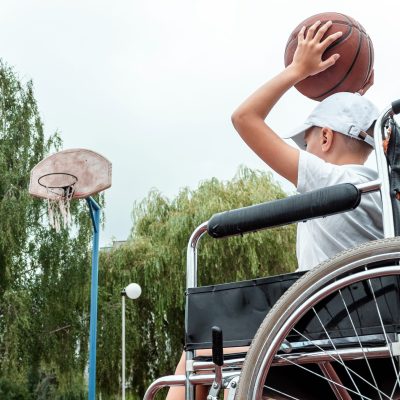 Concept of disabled child, support, rehabilitation, disabled person, paralyzed, happy disabled child. Disabled boy at school on the sports ground